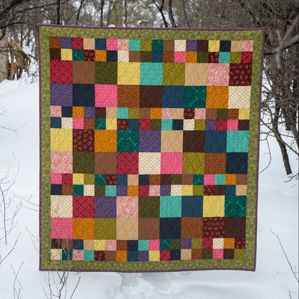 Colourful quilt hanging outdoors against a snowy background
